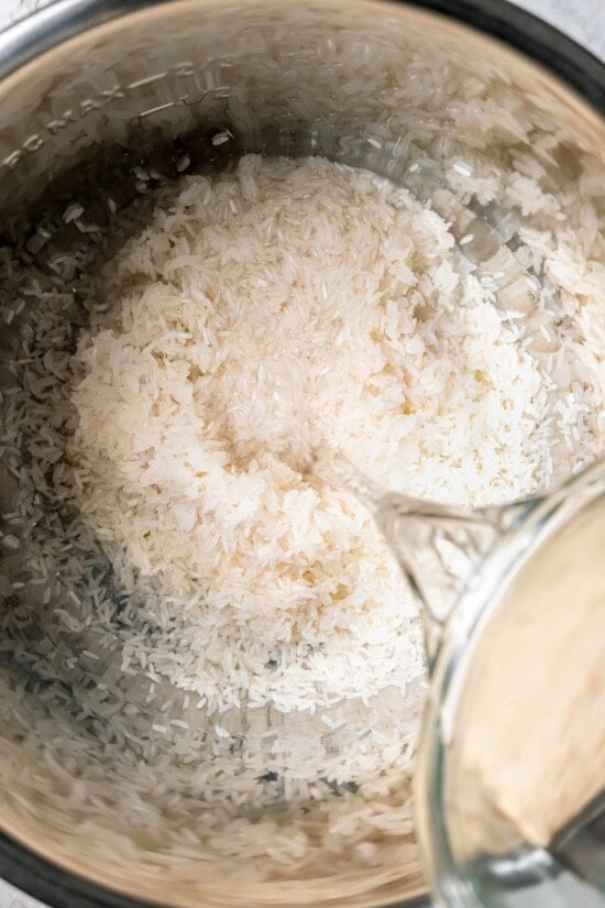 Jasmine rice is a fragrant rice perfect for pairing with curries and stir fries! Make it in the Instant Pot and it's easy, fluffy, and tasty. Pouring water into instant pot with rice
