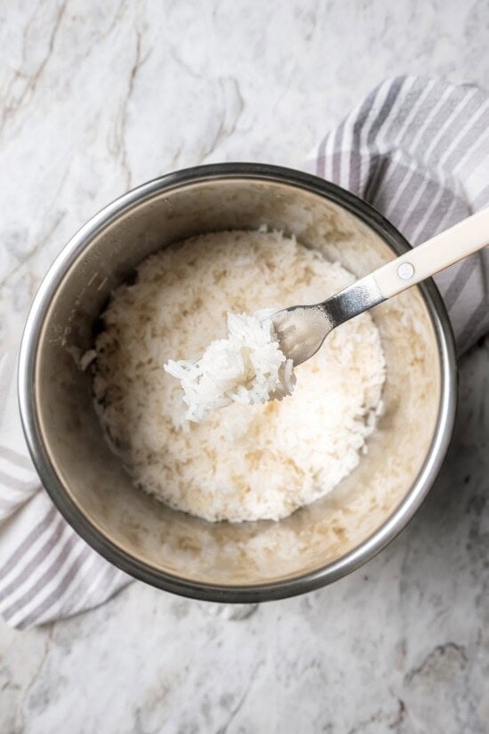 Jasmine rice is a fragrant rice perfect for pairing with curries and stir fries! Make it in the Instant Pot and it's easy, fluffy, and tasty. Forkful of jasmine rice held over pot