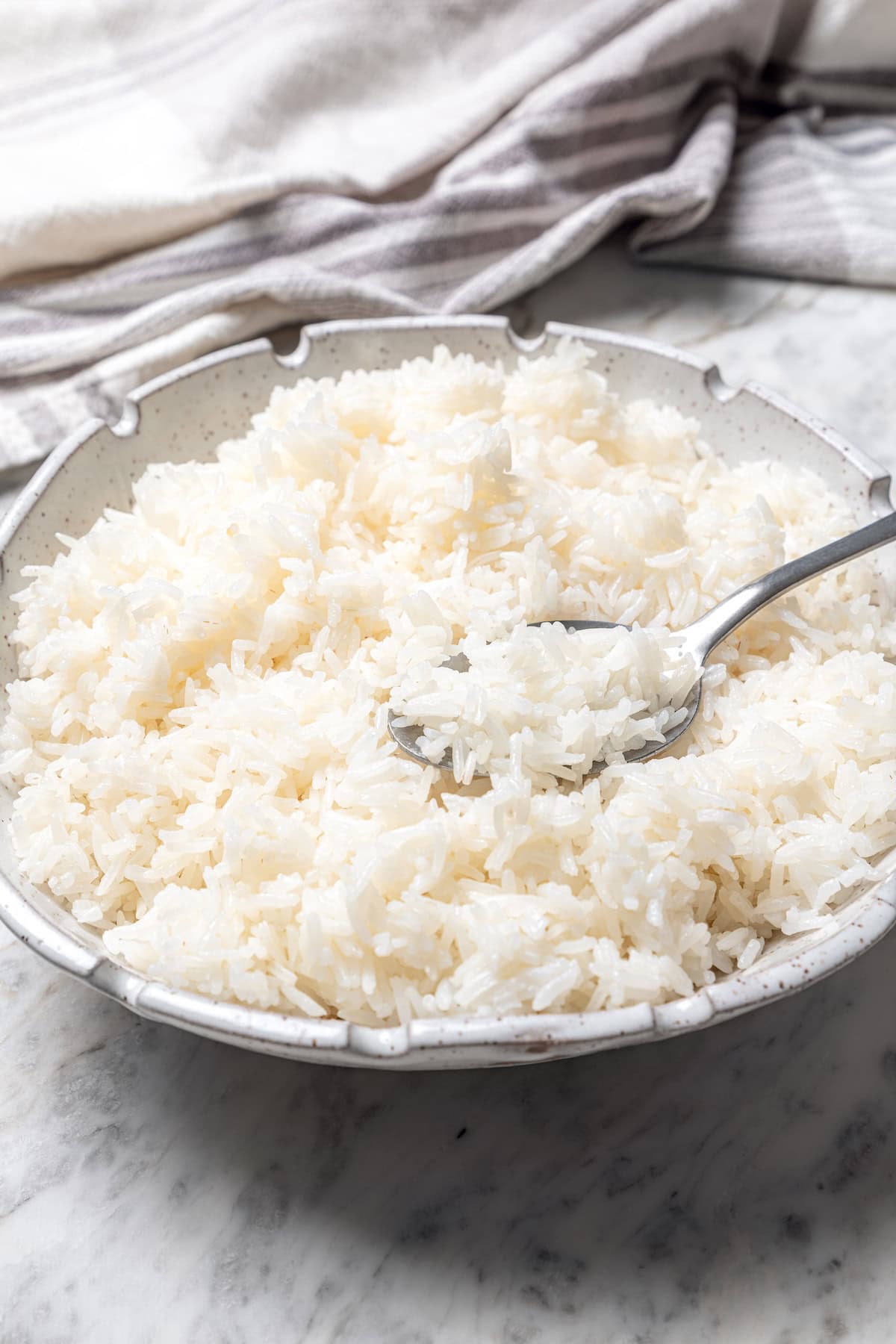 Jasmine rice is a fragrant rice perfect for pairing with curries and stir fries! Make it in the Instant Pot and it's easy, fluffy, and tasty. Bowl of jasmine rice with spoon