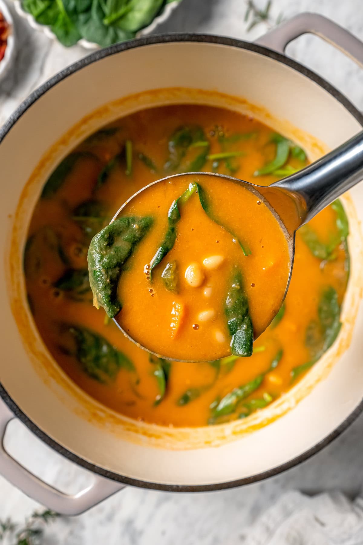 Ladle of navy bean soup held over pot