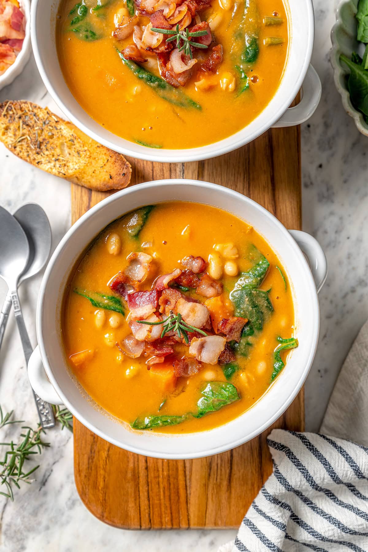 Two bowls of navy bean soup with bacon