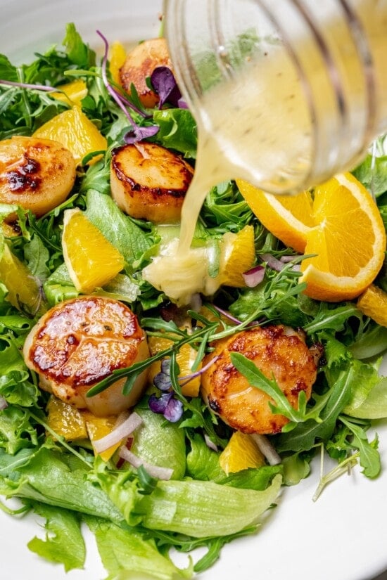 Pan seared scallops taste like a special occasion dinner but they’re easy enough for a weeknight. Serve over salad for a light, healthy meal! Pouring mojo vinaigrette onto scallop salad