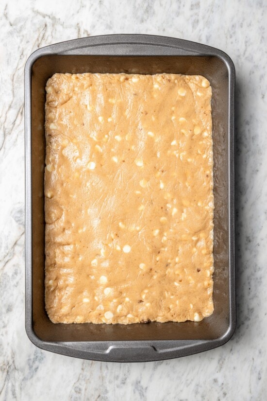 Overhead view of sugar cookie dough with white chocolate chips on sheet pan