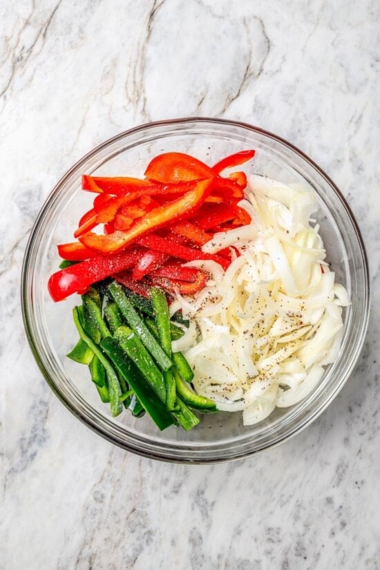 Overhead view of seasoned red peppers, poblanos, and onions in bowl