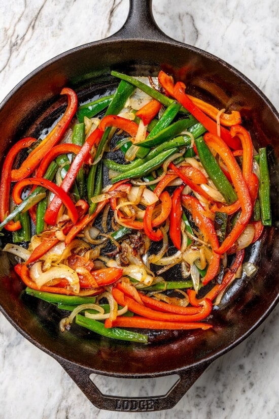 Overhead view of peppers and onions in cast iron skillet
