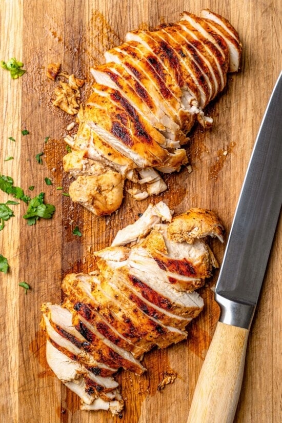 Overhead view of sliced chicken on cutting board with knife