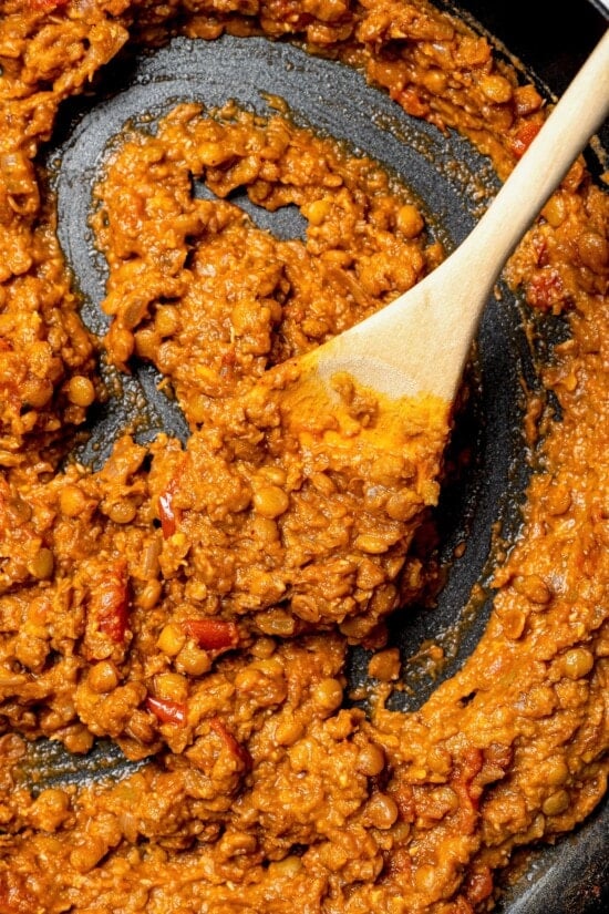 Overhead view of lentil taco filling in skillet with wooden spoon