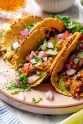 Plate with 3 lentil tacos topped with cilantro and red onion