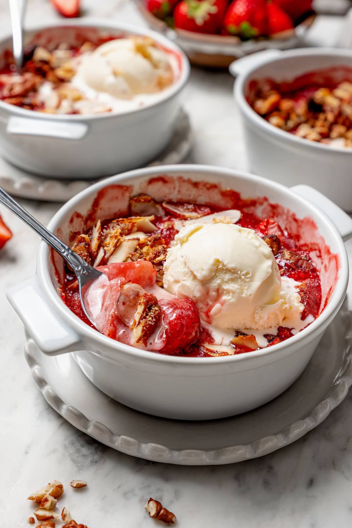 Strawberry crisp in bowl with scoop of ice cream and spoon