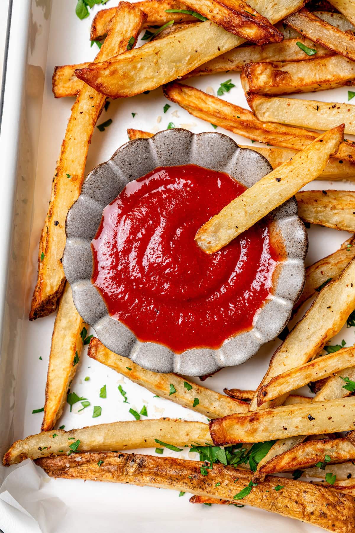 French fry dipping into small bowl of ketchup