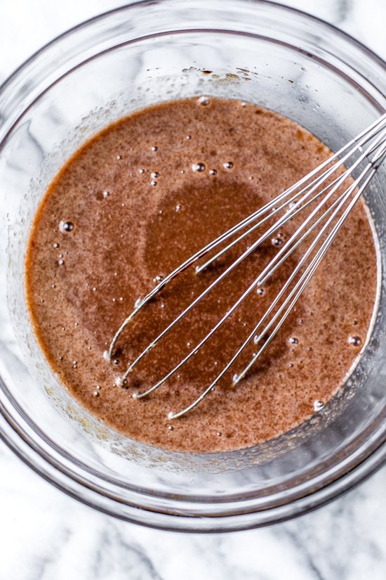 Overhead view of wet ingredients for chocolate zucchini bread in bowl with whisk
