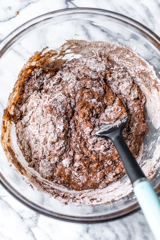 Overhead view of dry ingredients added to bowl of wet ingredients for chocolate zucchini bread