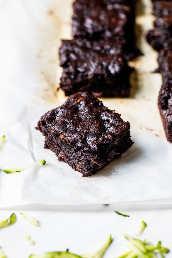 Flourless chocolate zucchini brownie on parchment paper, with additional brownies in background