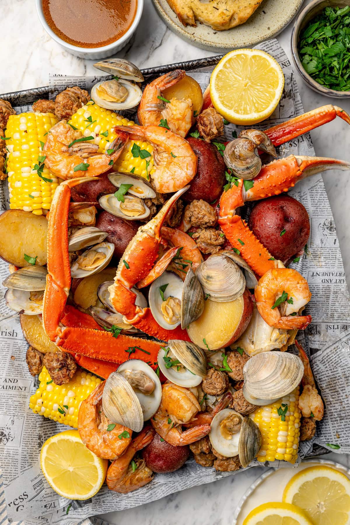 Overhead view of seafood boil arranged on newspaper-lined sheet pan