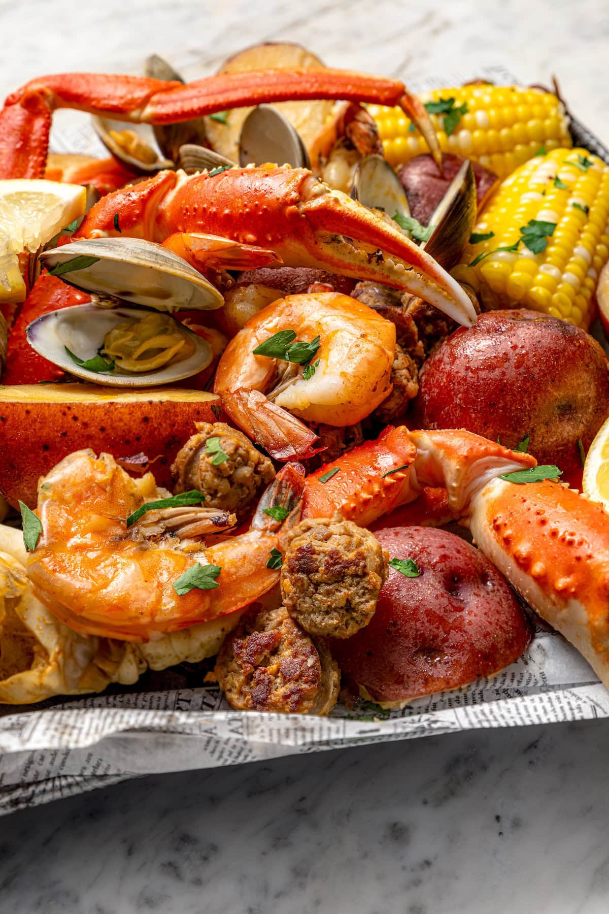Closeup of seafood boil with crab legs, chorizo, shrimp, and clams