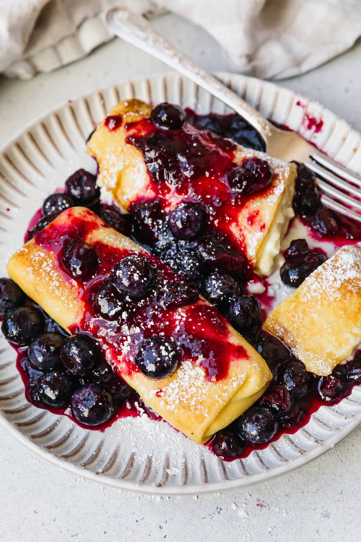 Cooked cheese blintzes on plate with blueberry sauce