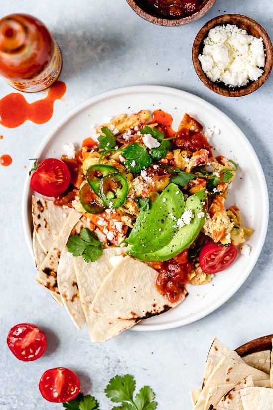 Overhead view of migas on plate with tortillas and avocado