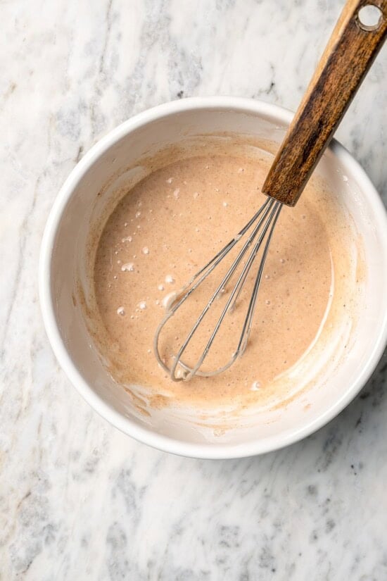 Buttermilk gives these spiced apple scones a moist, tender crumb, while applesauce replaces much of the butter to lighten them up! Overhead view of spiced glaze in bowl with whisk