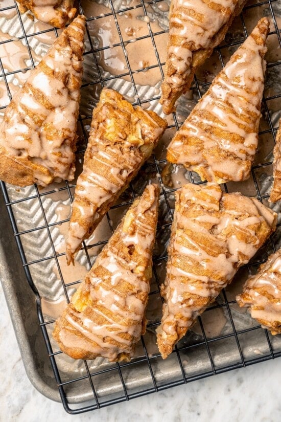 Buttermilk gives these spiced apple scones a moist, tender crumb, while applesauce replaces much of the butter to lighten them up! Overhead view of apple scones drizzled with spiced glaze