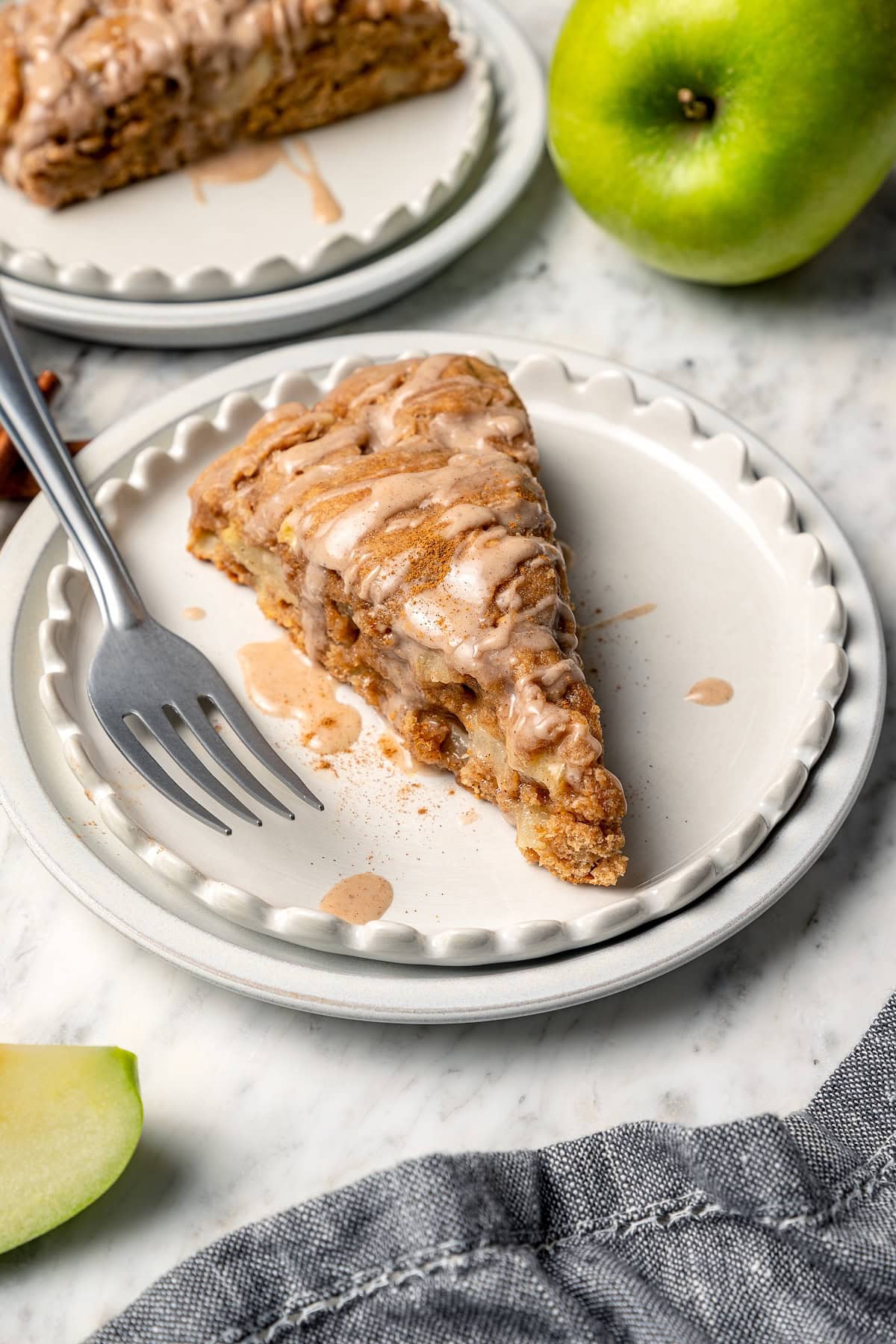 Buttermilk gives these spiced apple scones a moist, tender crumb, while applesauce replaces much of the butter to lighten them up! Apple scone on plate with fork