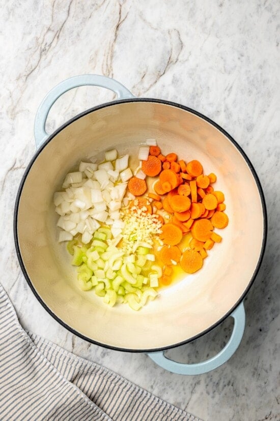 This rich, creamy Chicken Corn Chowder is thickened with potatoes and pureed corn instead of heavy cream to keep it light. Easy and delicious! Carrots, celery, onion, and garlic in dutch oven.
