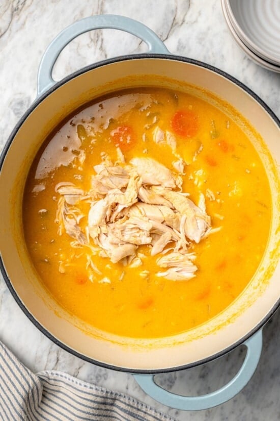 This rich, creamy Chicken Corn Chowder is thickened with potatoes and pureed corn instead of heavy cream to keep it light. Easy and delicious! Chicken added to pot of corn chowder.