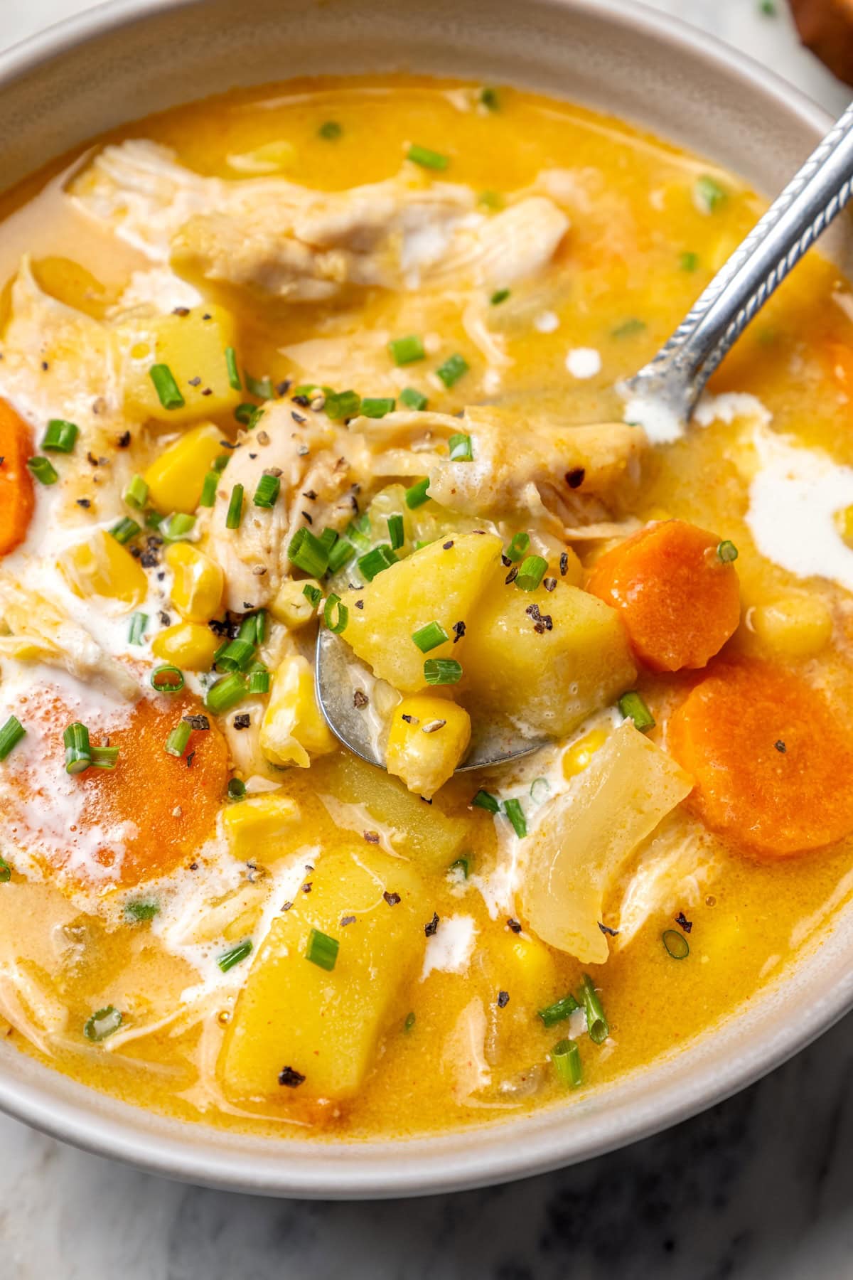 This rich, creamy Chicken Corn Chowder is thickened with potatoes and pureed corn instead of heavy cream to keep it light. Easy and delicious! Bowl of chicken corn chowder with spoon.