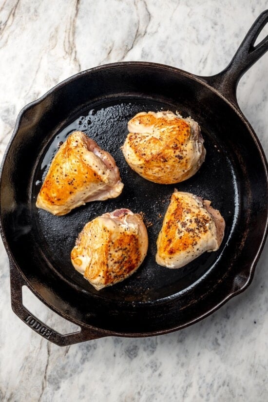 Chicken breast halves browning in cast iron skillet.
