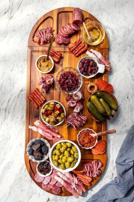Charcuterie board in process, with bowls and meats.