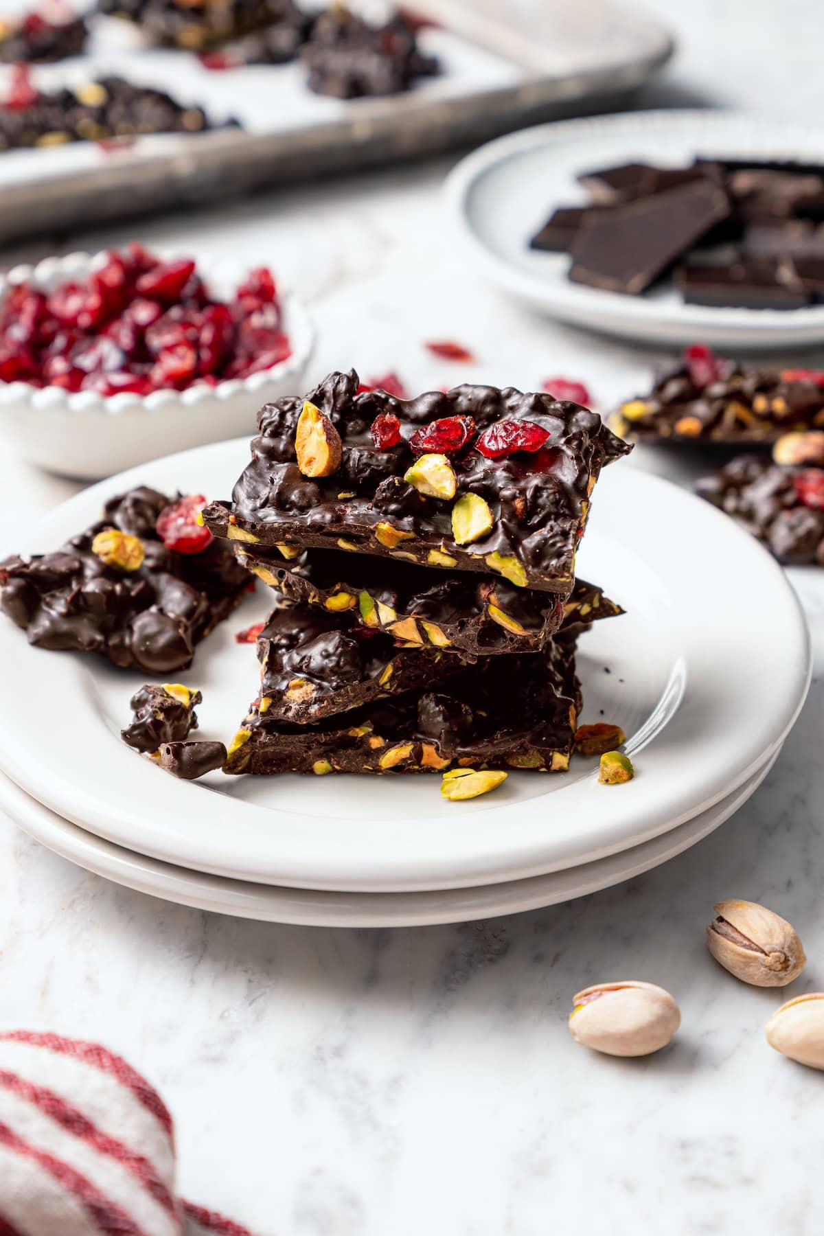 Stack of dark chocolate bark with pistachios and cranberries on plate.