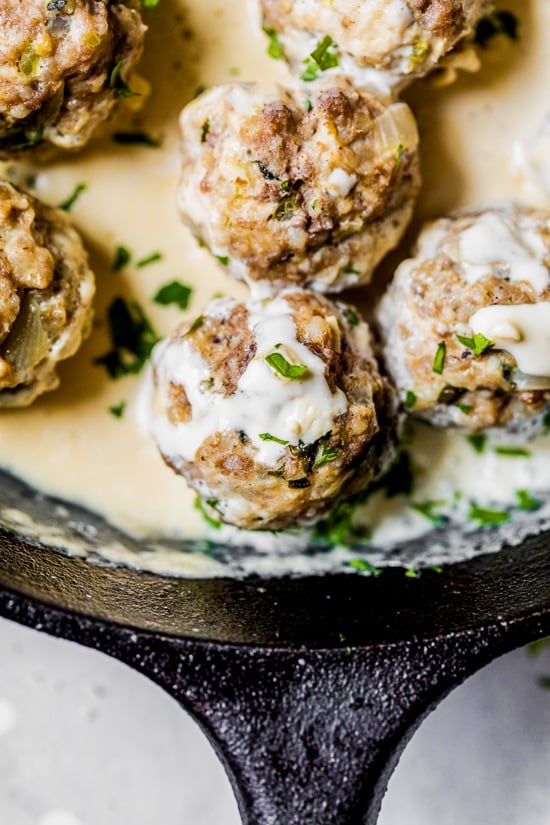 Closeup of creamy Swedish meatballs with gravy in cast iron skillet.