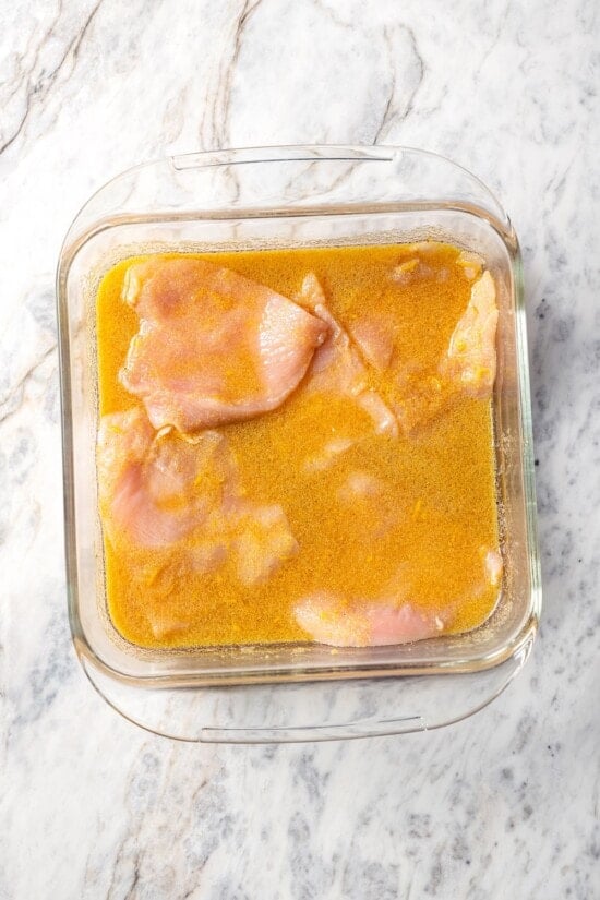 Chicken breasts in pan of marinade.