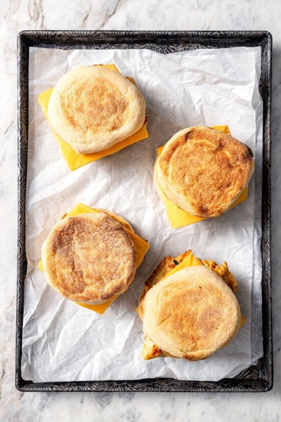 4 copycat Chick-fil-A egg white grill sandwiches on parchment lined sheet pan.