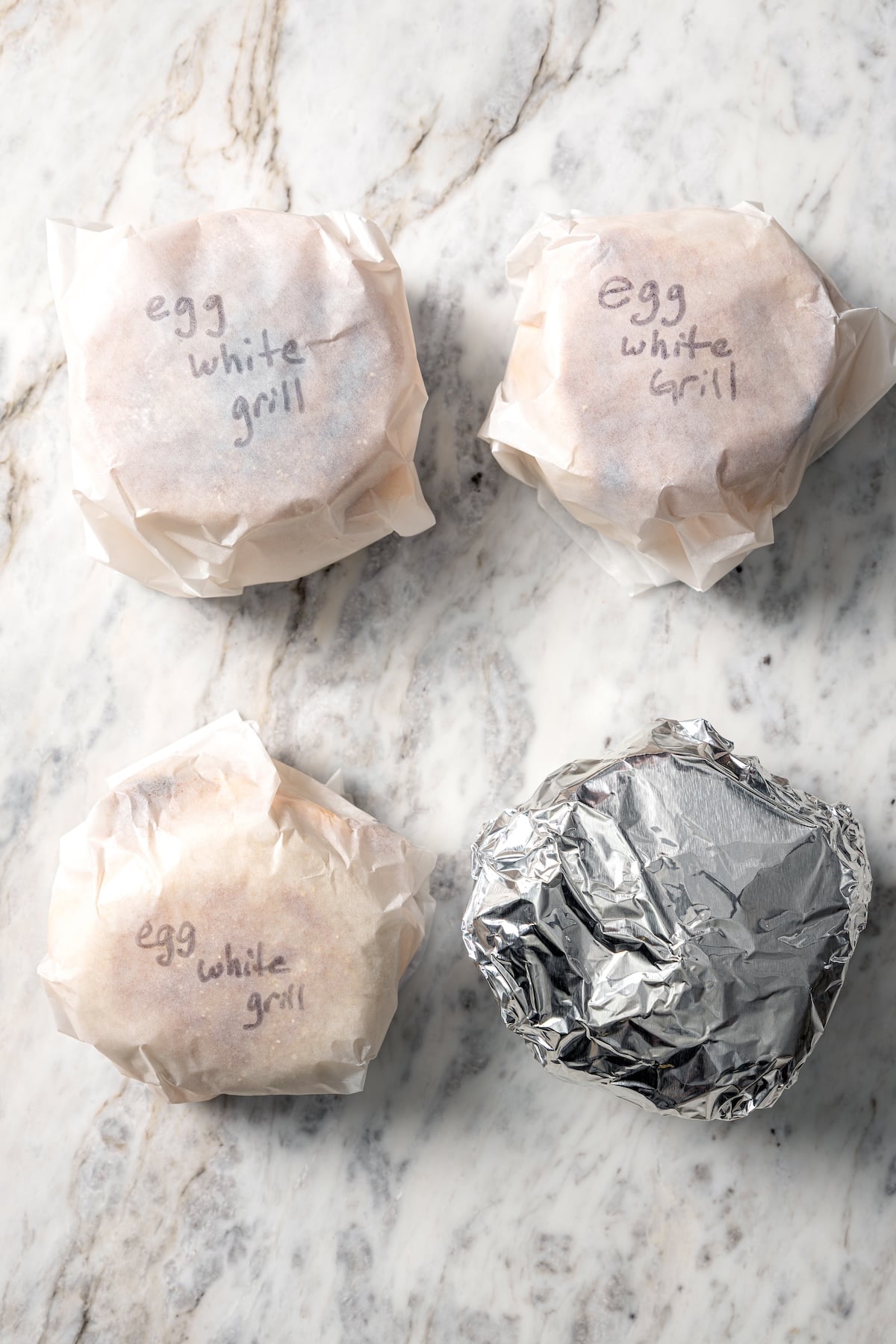 3 egg white grill sandwiches wrapped in parchment paper and one wrapped in foil.