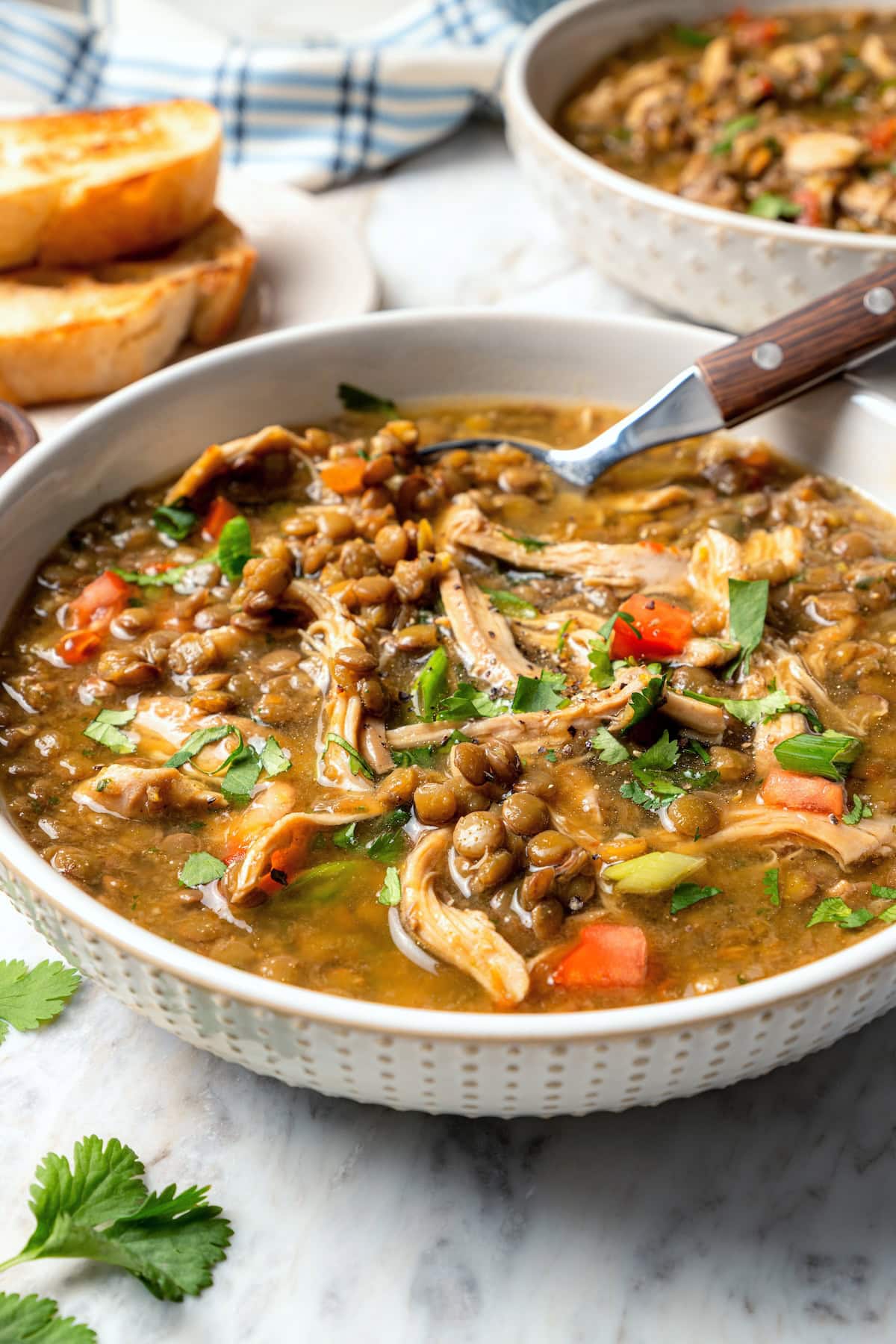 Bowl of chicken lentil soup with spoon.