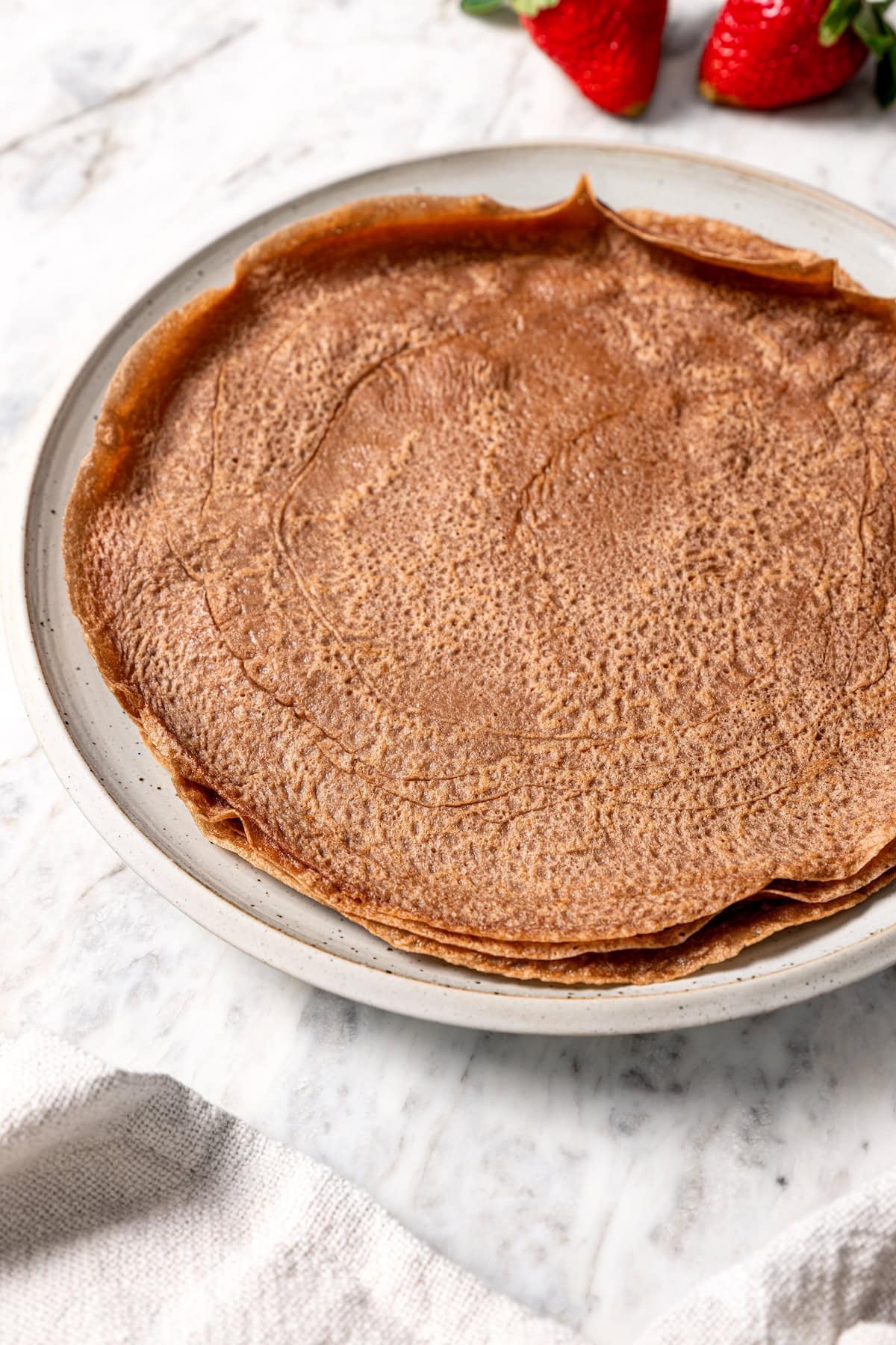 Stack of chocolate crepes on plate.