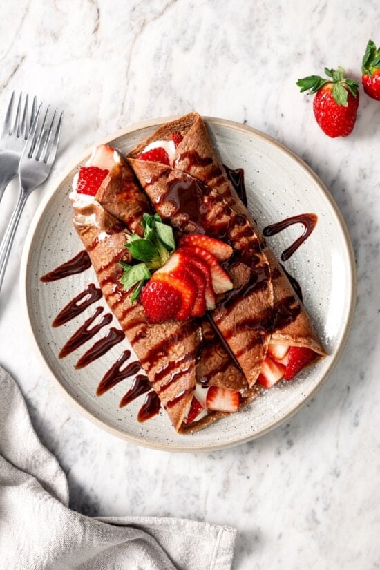Plate of chocolate crepes with Cool Whip and strawberries.