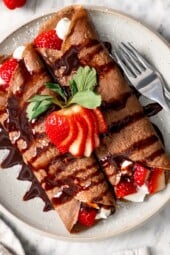 Plate of chocolate crepes with strawberries.