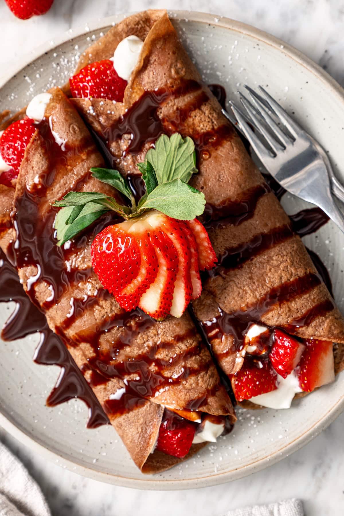 Plate of chocolate crepes with strawberries.