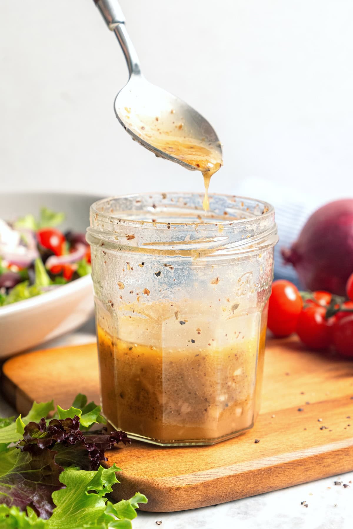 Spoonful of Greek salad dressing held over jar.