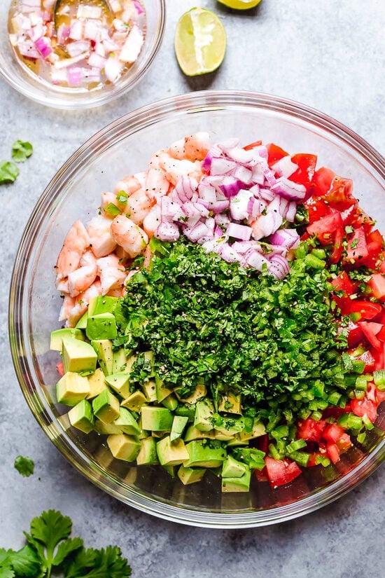 Shrimp and Avocado Salad ingredients with tomatoes and cilantro, in a bowl.