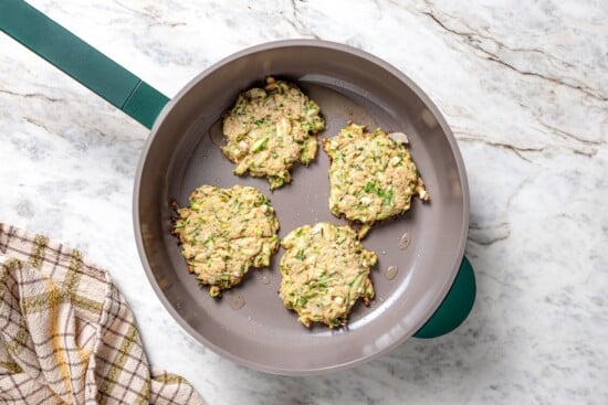 Zucchini fritters in skillet.