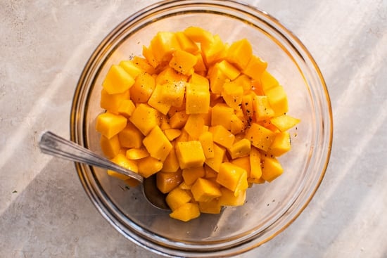 This easy maple roasted butternut squash is a quick fall side dish with cubed squash tossed in pure maple syrup. Perfect for holiday dinners! Cubed butternut squash in a glass bowl.