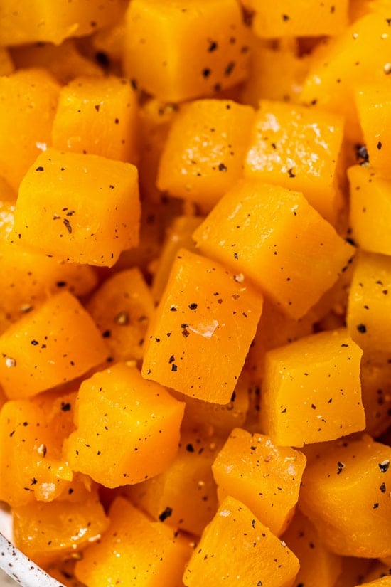 This easy maple roasted butternut squash is a quick fall side dish with cubed squash tossed in pure maple syrup. Perfect for holiday dinners! Close up of maple roasted butternut squash in a large bowl.